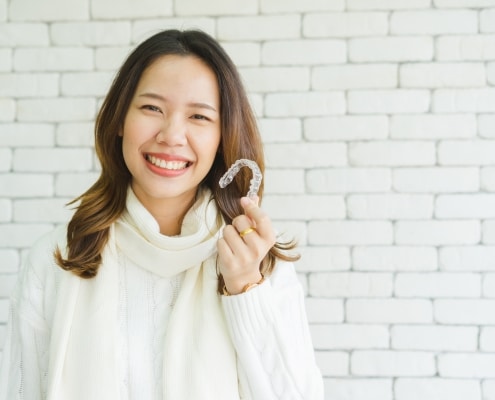 Woman holding her Invisalign tray