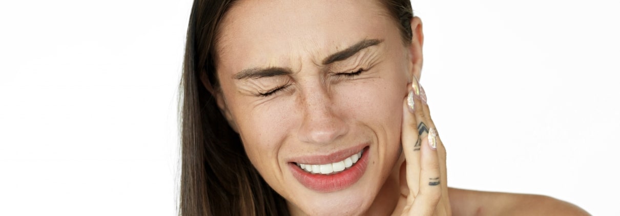 Woman holds fingers on her cheek showing toothache