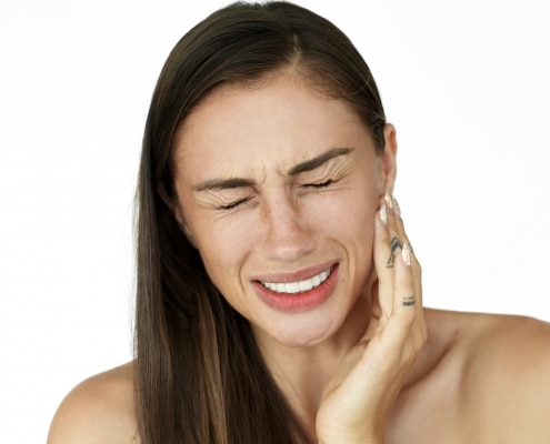 Woman holds fingers on her cheek showing toothache