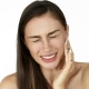 Woman holds fingers on her cheek showing toothache