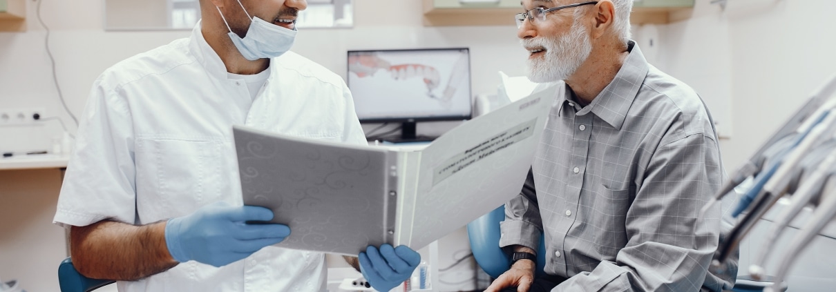 Older man siting with his dentist discussing treatment