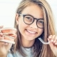 Dental invisible braces or silicone trainer in the hands of a young smiling girl. Orthodontic concept - Invisalign.