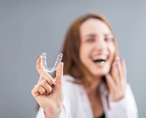 girl laughing while holding an Invisalign clear aligner