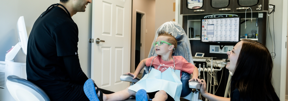 kid sitting on the dental chair and Dr. Desai talking to the child