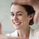 middle aged woman smiling while holding her hands as if taking a photo